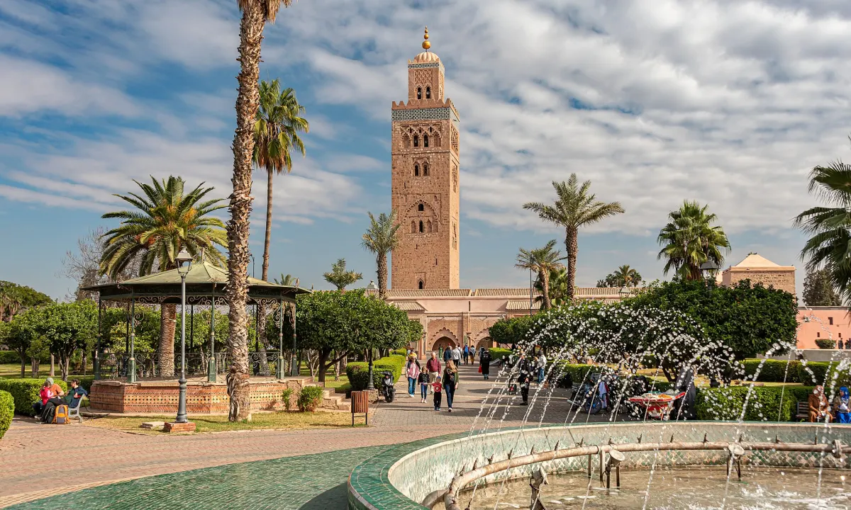 The Koutoubia minaret seen over palms and a fountain in the park beside it